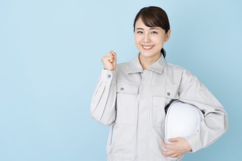 ヘルメットを持ってガッツポーズする作業着女性